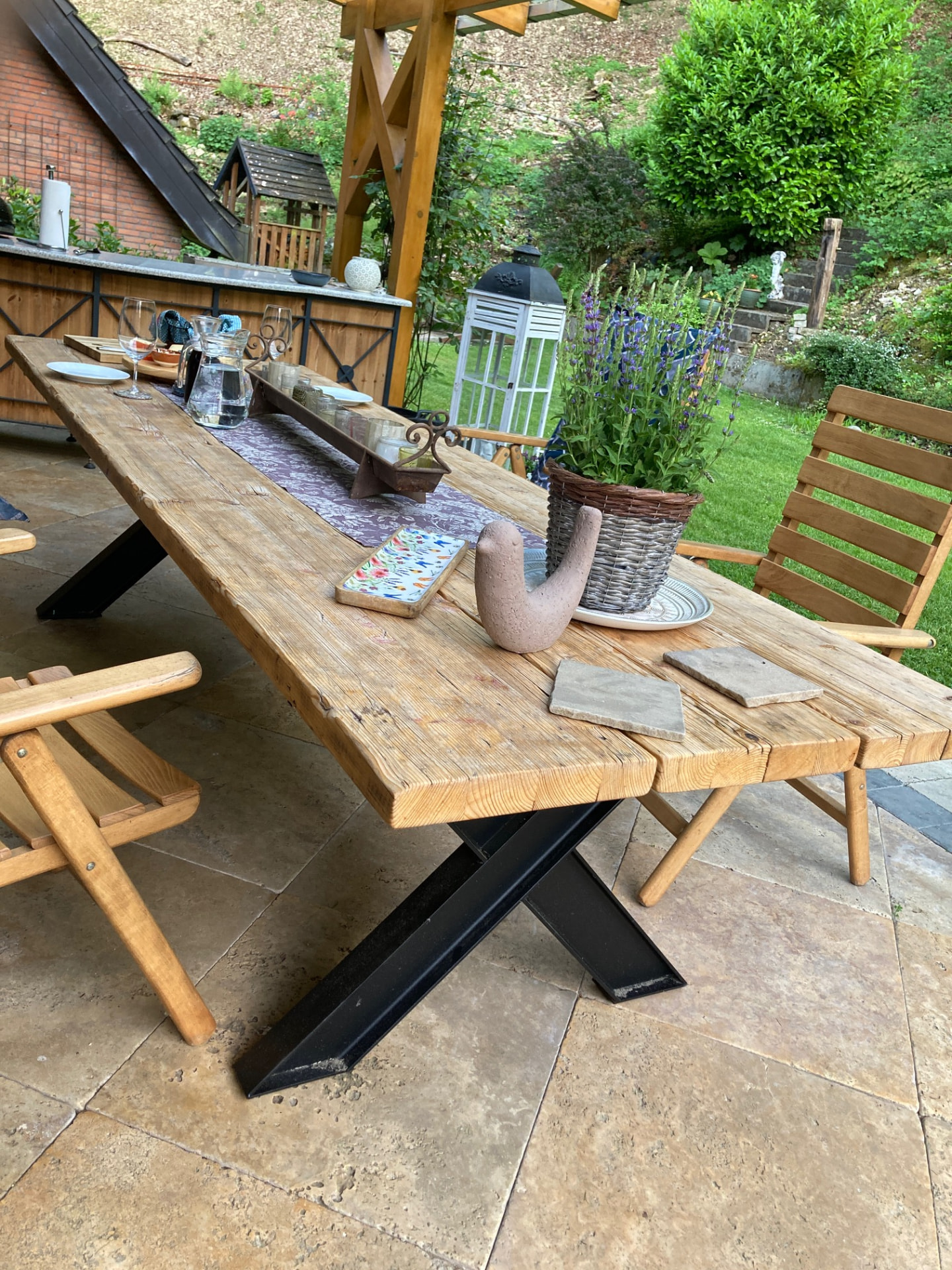 Handgefertigter Gerüstbohlentisch von OMH Wood & More mit massivem X-Stahlgestell auf einer Terrasse