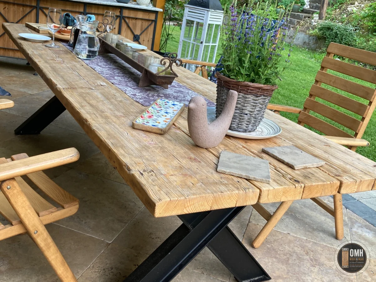 Handgefertigter Gerüstbohlentisch von OMH Wood & More mit massivem X-Stahlgestell auf einer Terrasse